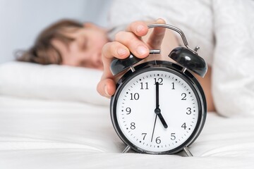 Sleeping woman on pillow with alarm clock before waking up