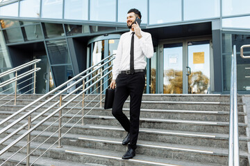 business man walking down the stairs and talking on the phone in the street