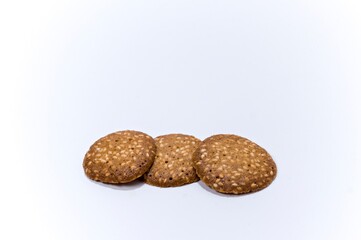 Three sesame cookies lying in a row on a white background