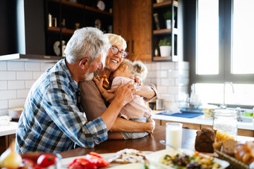 Happy grandparents with grandchildren making breakfast in kitchen