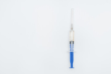 One single syringe with dose of medicine or vaccine on white or gray background with a place for the text: vaccinations against influenza coronavirus, side view, soft focus, selective focus