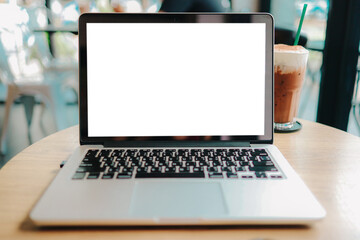 Fototapeta premium Laptop with Mock up blank screen on wooden table in front of cafe space for text. product display montage- technology concept.