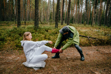 Funny man pulling a pink boot of funny woman in the forest