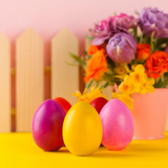 Easter colorful eggs on the background of spring flowers. Bright Easter concept. Copy space.
