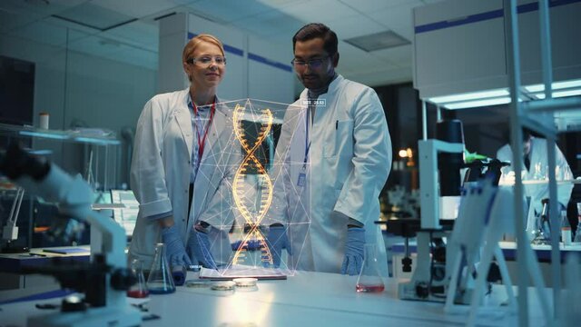 Female and Male Medical Industry Scientists Have Conversation and Use Futuristic Augmented Reality Technological Interface in Modern Science Laboratory. DNA Hologram Appears in Front of Research Team.