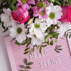 Pink letterboard with quote Hellow Spring and blooming tender bouquet of flowers. Top view. Festive greeting card
