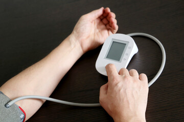 Male hands with blood pressure monitor, man measuring the pressure. Health care and cardiology concept