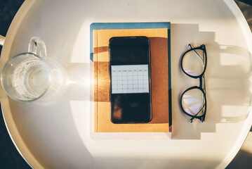 Notepad and mobile phone with calendar . Concept of business. Planning work at home with planner, pen, glasses.
