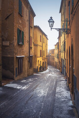 Fototapeta na wymiar Volterra old town street during a snowfall in winter. Tuscany, Italy