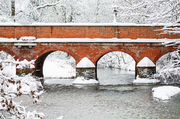 Winter waterway scene with two bridges that are covered in snow