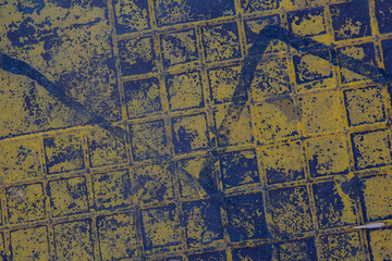 Fototapeta na wymiar The texture of a manhole cover drenched in yellow paint.