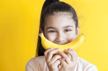 Happy little child girl with yellow banana like smile on yellow background.