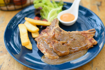 Pork chop french fries sot on a blue plate on a wooden table