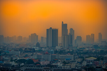 Fototapeta premium The blurred abstract background of the morning sun exposure to the tiny dust particles that surround the tall buildings in the capital, the long-term health issue of pollution