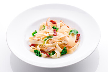 tagliatelle pasta with chicken, mushrooms and sun-dried tomatoes on a white plate on a withe background. close-up. photo for clipping. for the menu
