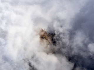 lone mountainpeak poking through a sea of low hanging clouds