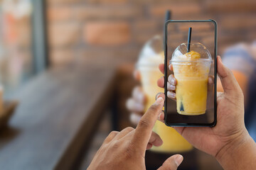 Male hands taking photo with mobile smartphone on orange juice,Young person having fun with new technology apps for social media ,food delivery concept.