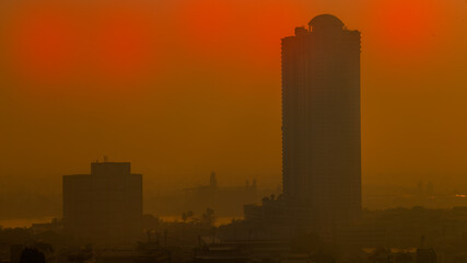 Fototapeta na wymiar The blurred abstract background of the morning sun exposure to the tiny dust particles that surround the tall buildings in the capital, the long-term health issue of pollution