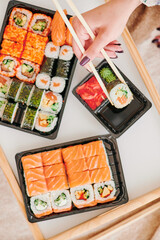 Girl eating sushi. Sushi delivery concept, sushi in plastic container delivered to home