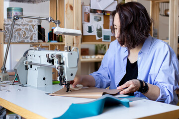 Woman designer working on sewing machine and making leather goods, hand maker create in workshop