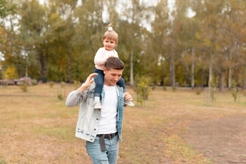 Happy young father on a walk with little daughter on his neck.