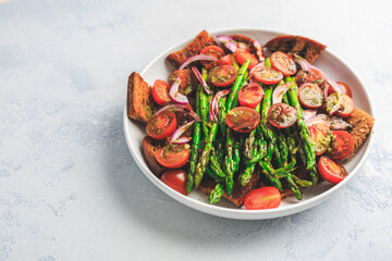 Warm green asparagus salad with tomato, onion and roaster bread
