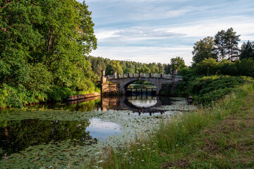 Fototapeta na wymiar View of the Slavyanka River and the Viscontiev Bridge in the Pavlovsk Palace and Park Complex on a summer day, Pavlovsk, Saint Petersburg, Russia