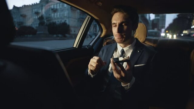 Angry business man swearing in voice chat on mobile phone in dark car.