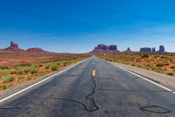 Fototapeta na wymiar Scenic view of the Monument Valley with the sandstone buttes and a road on the foreground; Concept for travel in the USA and road trip.