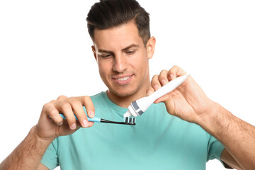 Man applying toothpaste on brush against white background