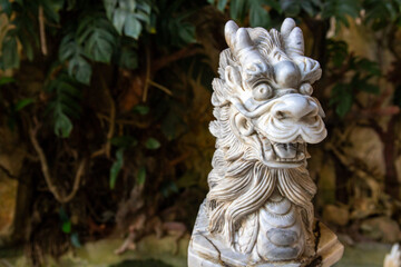 Dragon stone carved statue on green garden background. Chinese zodiac animal sculpture. Marble dragon statue