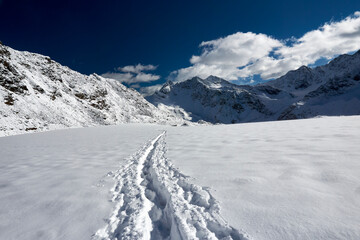 Fototapeta na wymiar tracks in the snow leading to distant mountain peaks in famous Kaunertal in Austrian Alps