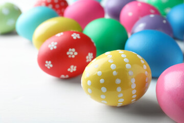 Fototapeta na wymiar Bright painted eggs on white wooden table, closeup. Happy Easter