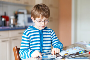 Adorable little kid boy with glasses reading book. Cute happy school child and student learning letters and read. Funny boy making preschool homework. Education concept