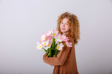curly haired teen girl hold  bouquet of spring pink tulips on a white background
