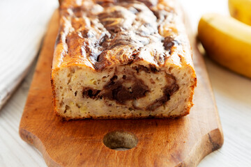 Homemade Chocolate Banana Bread on a rustic wooden board on a white wooden background, side view. Close-up.