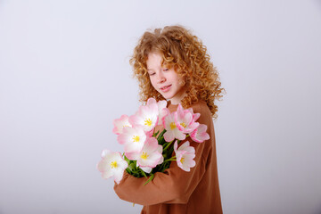 curly haired teen girl hold bouquet of spring pink tulips on a white background