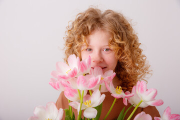 Obraz na płótnie Canvas curly haired teen girl hold bouquet of spring pink tulips on a white background