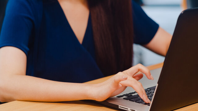 Successful beautiful executive Asia young businesswoman smart casual wear watching tutorial about creative ideas at laptop computer during working process in modern office workplace. Close up shot.