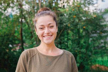 Young woman smiling outdoor. Beautiful brunete girl resting on park or garden green background. Free happy woman at summertime. Freedom happiness carefree happy people concept.