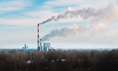 Thermal power plant in the city of Warsaw, Poland. Steam smoke comes out of the power plant's chimney, supplying heat and sending it into the atmosphere. 