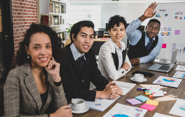 selective focus on African american business men raising their hands to inquire about a business meeting and attendees of different nationalities with smiling faces in the office meeting room.