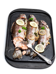 Baked rainbow trout with lemon and spices on grill tray isolated on white