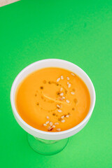 Pumpkin soup in a white plate on a green background. Close-up. Photo for clipping, for the menu