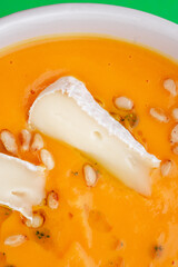Pumpkin soup with eringi mushrooms in a white plate on a green background. Close-up. Photo for clipping, for the menu