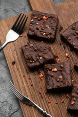 Homemade chocolate brownies with dry fruits and choco drops with old silverware on dark oak cutting...
