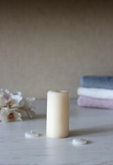 Fototapeta na wymiar a light candle stands on the table against the background of rolled towels and flowers