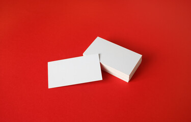 Photo of blank business cards on red paper background. Template for branding identity.
