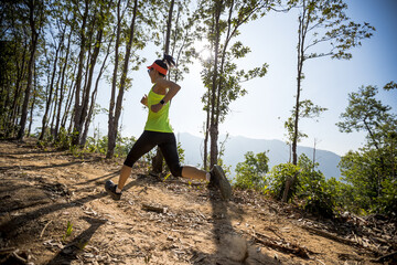 Young woman trail runner running on sunrise tropical forest mountain peak