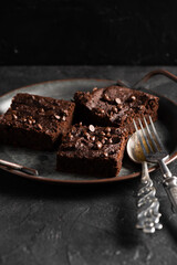Homemade comfort food. Yummy chocolate brownies with dry srawberries pieces and choco drops on dark...
